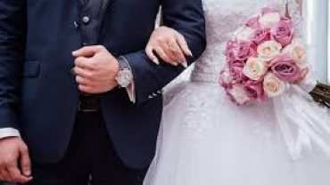 a man in a suit and tie next to a bouquet of flowers